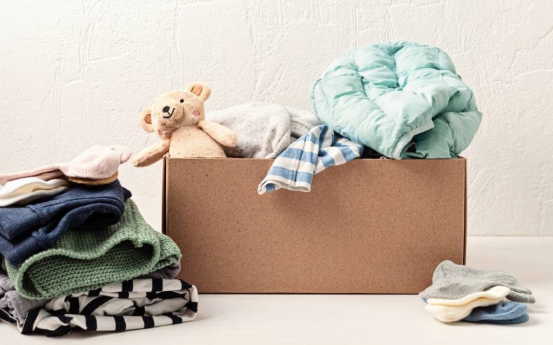 Baby and child clothes, toys in box. Second hand apparel idea. Circular fashion, donation, charity concept