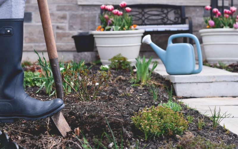 Woman in rubber boots digging a hole in a garden for planting